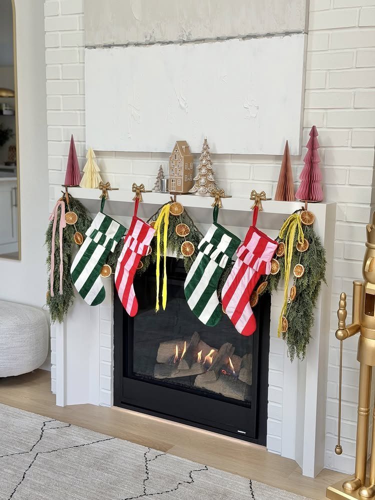 Mismatched red and green patterned stockings hanging on a white brick fireplace mantel.