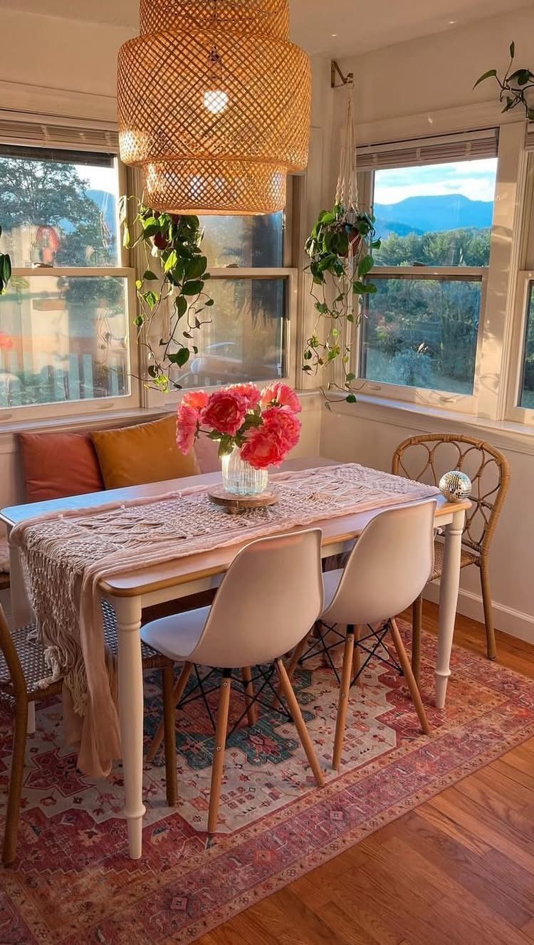 Dining area with hanging green plants by windows and a woven pendant light.