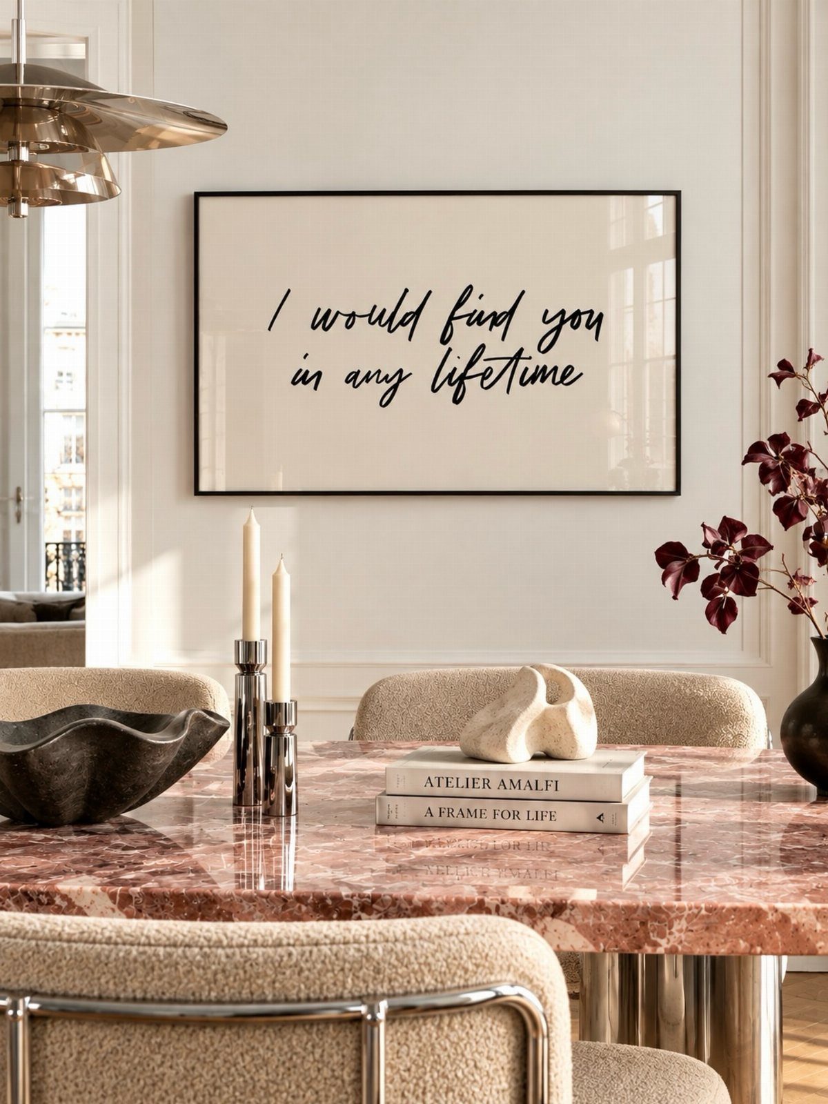 Framed cursive wall sign hanging above a marble dining table with candles.