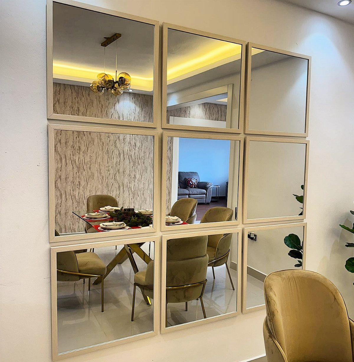 Grid of gold-framed mirrors reflecting a modern dining room with gold chairs.