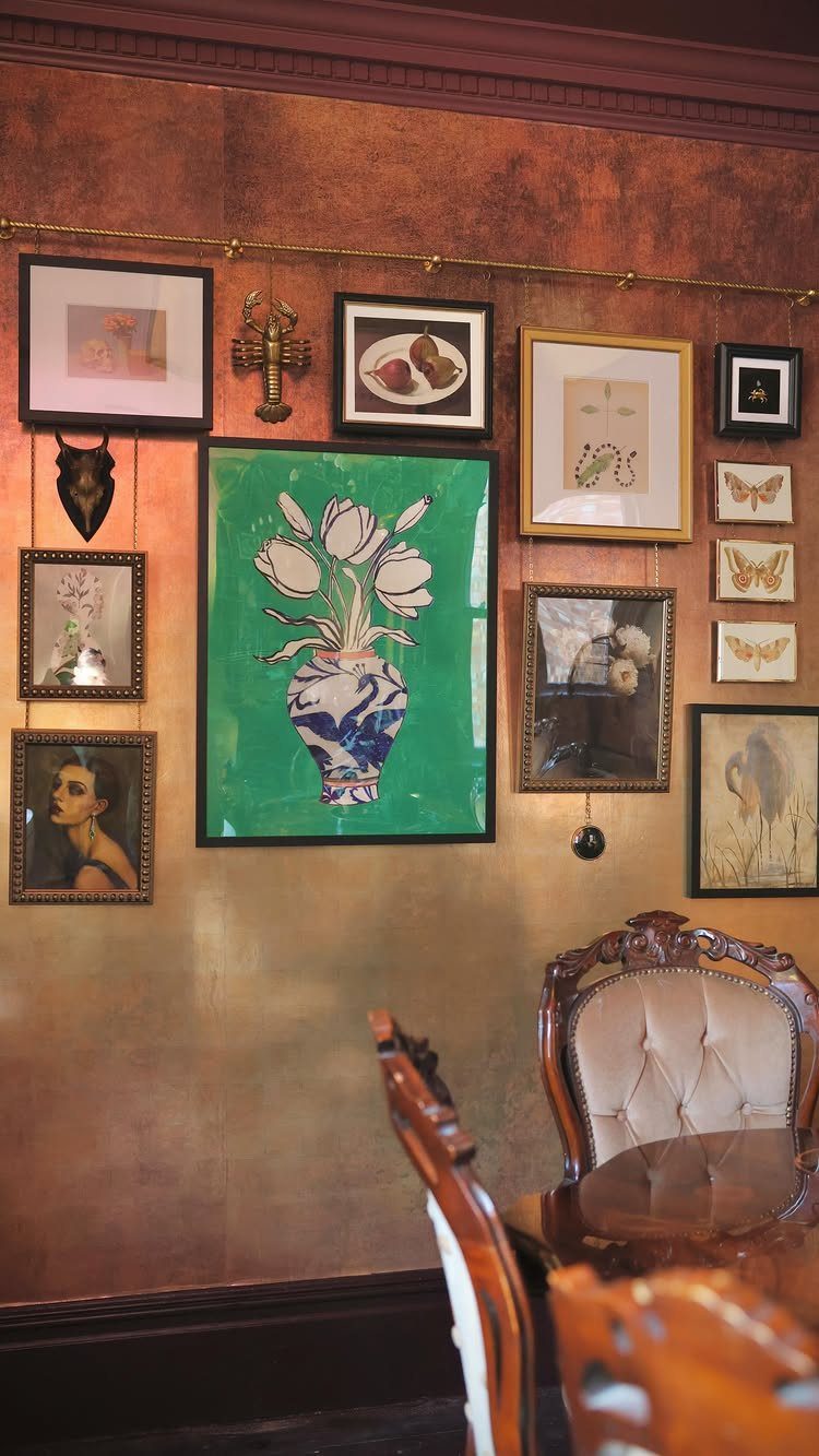 Gallery wall with framed art and a large flower painting on textured brown wall