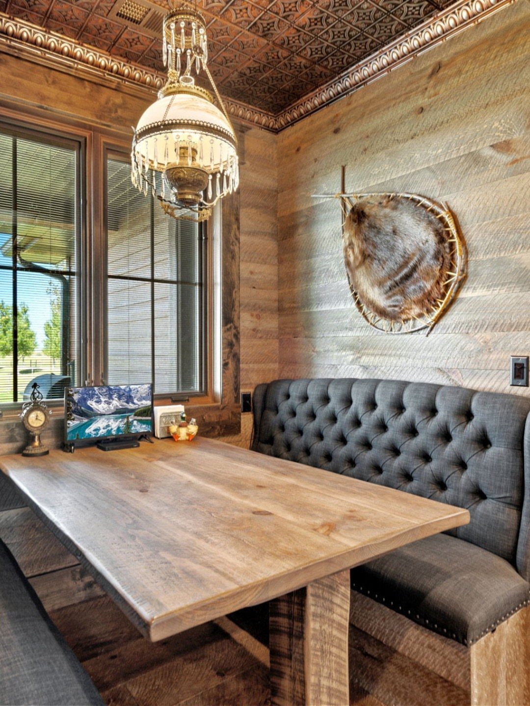 Reclaimed wood accent wall in a dining room with a grey tufted banquette.
