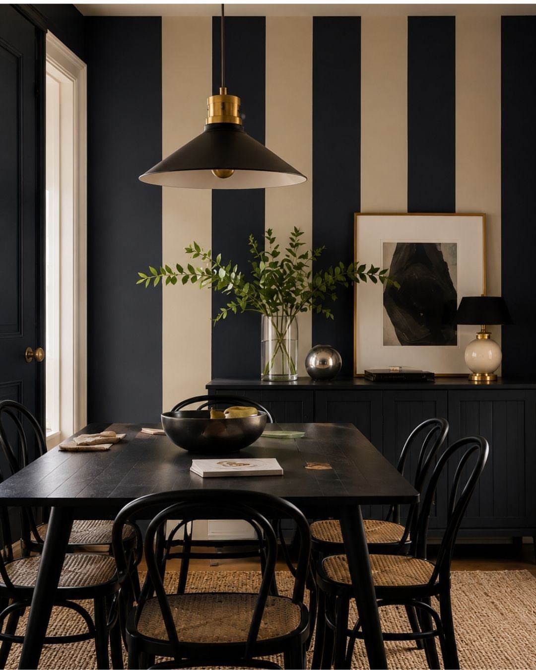 Dining room with navy blue and cream vertical striped accent wall and black furniture