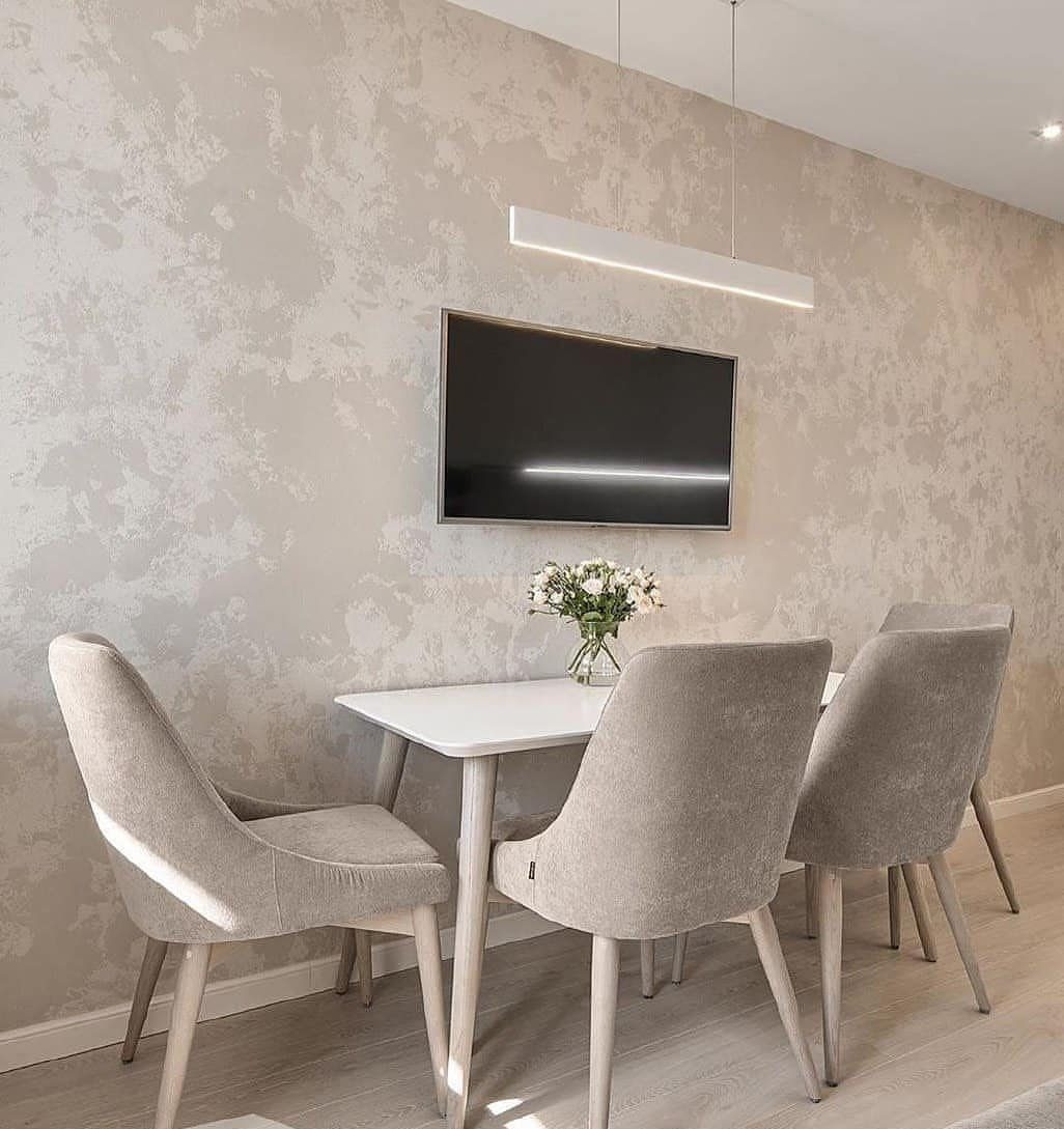 Textured plaster wall in a dining room with a white table and grey chairs.