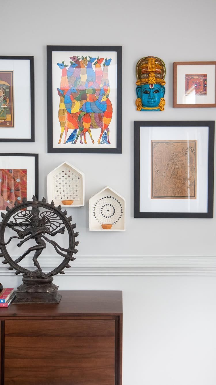 Gallery wall with framed art and sculptures above a dark wood buffet table.