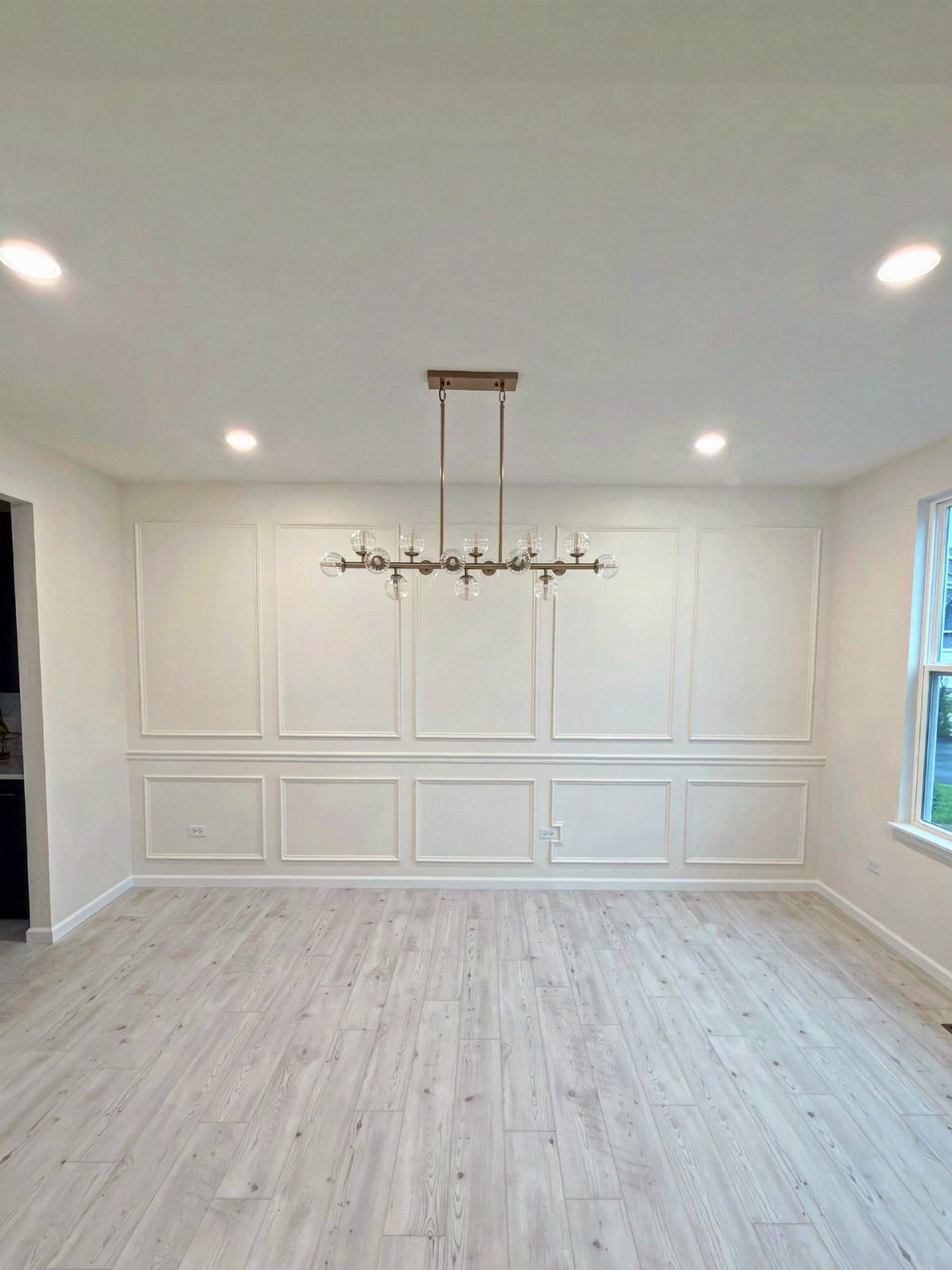 White dining room walls with a chair rail and decorative wainscoting panels.