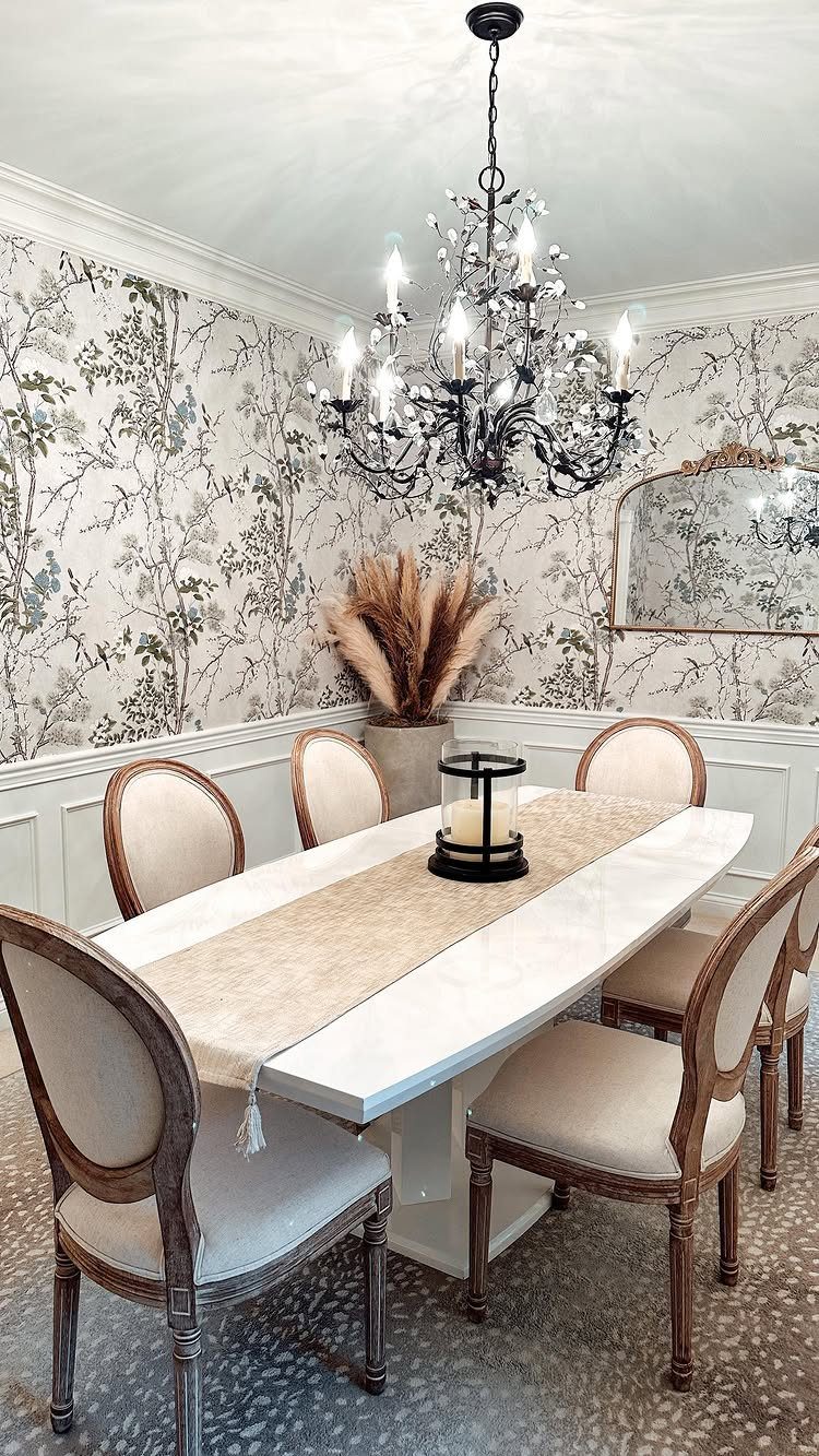 Dining room with white wainscoting chair rail, floral wallpaper, and a white table.