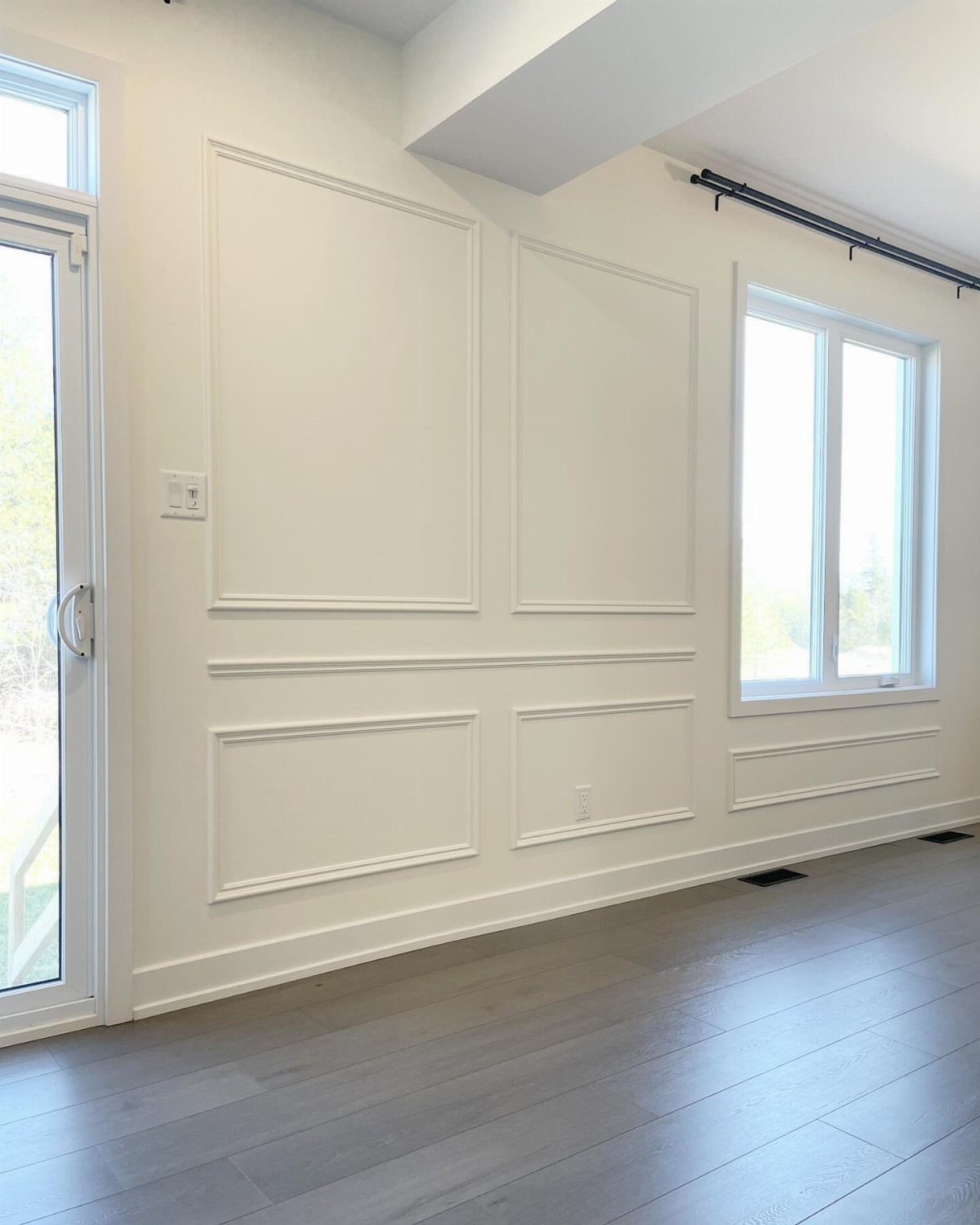 White wall with decorative chair rail molding and rectangular panels in a bright room