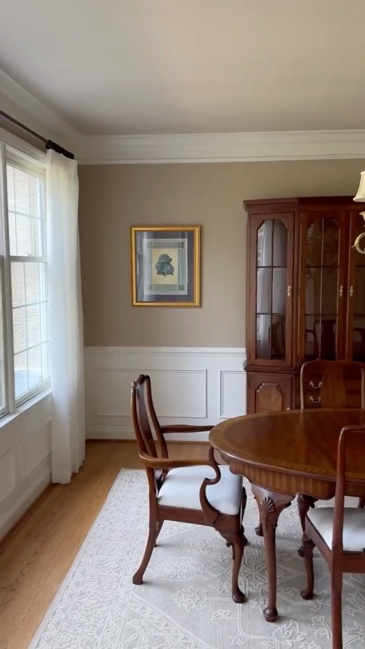 Dining room with white wainscoting chair rail, beige walls, and wooden furniture.