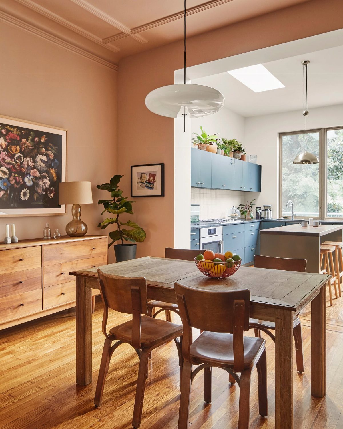 Dining room with apricot colored walls, wooden furniture, and blue kitchen cabinets.