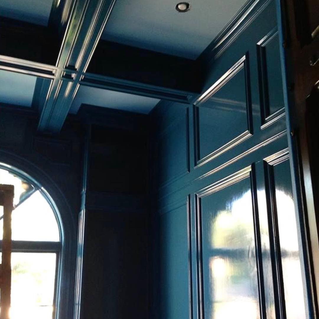 Deep blue high-gloss paneled walls and ceiling with a large arched window.
