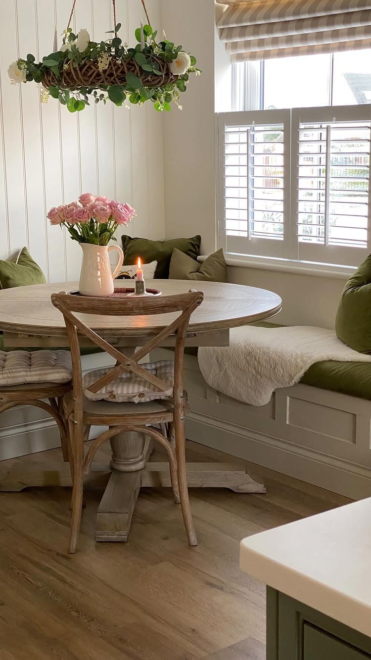 L-shaped bench seating with green cushions and a round pedestal dining table.