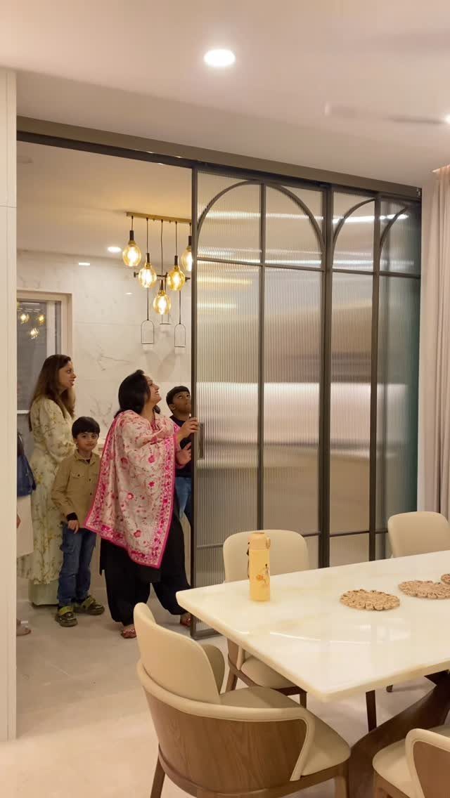 Modern dining room with white table, curved chairs, and frosted glass room divider.