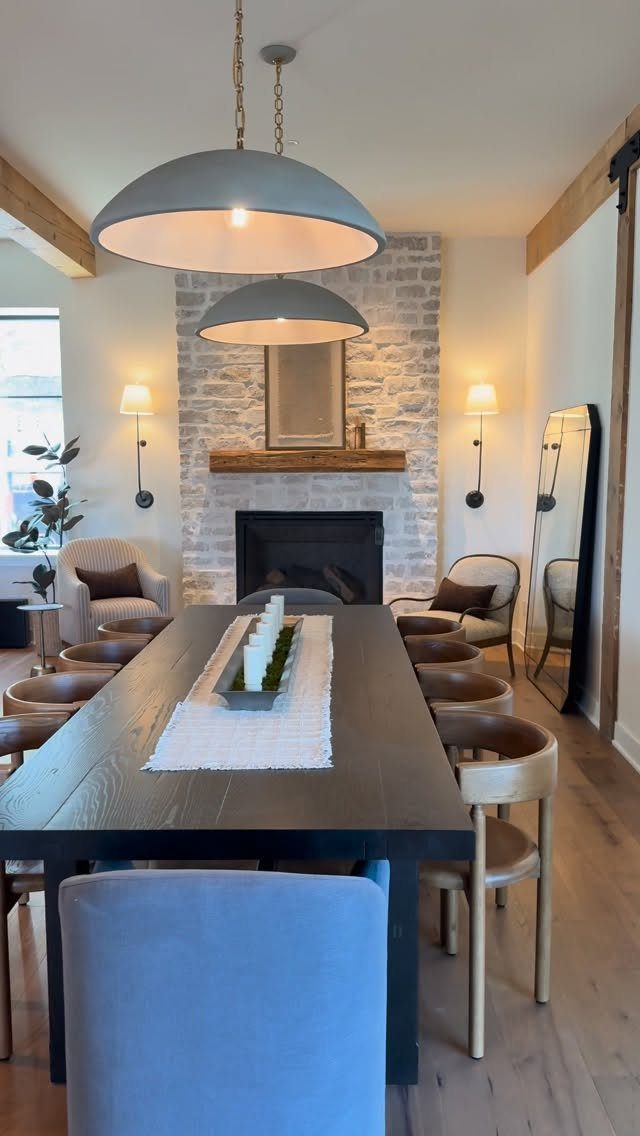 Dark wood dining table in a room with a white brick fireplace and pendant lights
