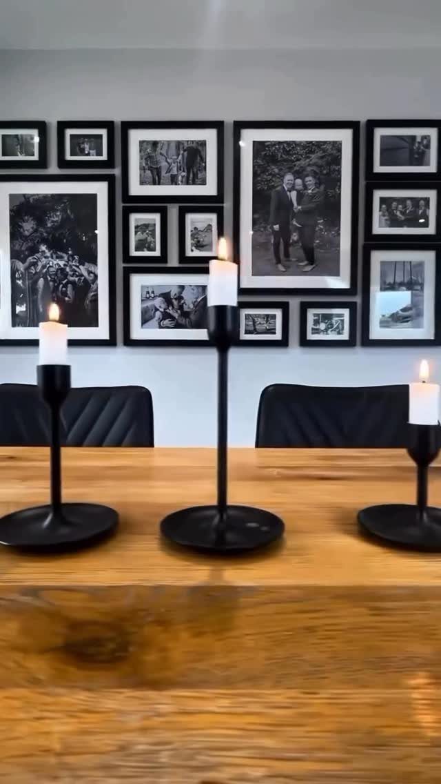 Black and white framed photos on a grey wall above a wooden dining table