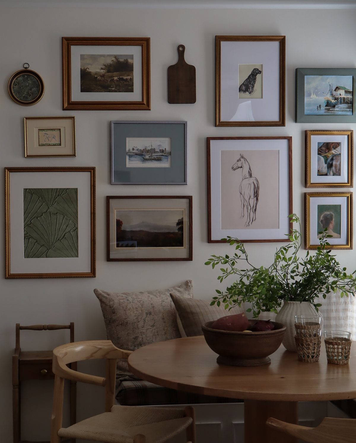 Gallery wall with curated framed art and a wooden board above a dining table
