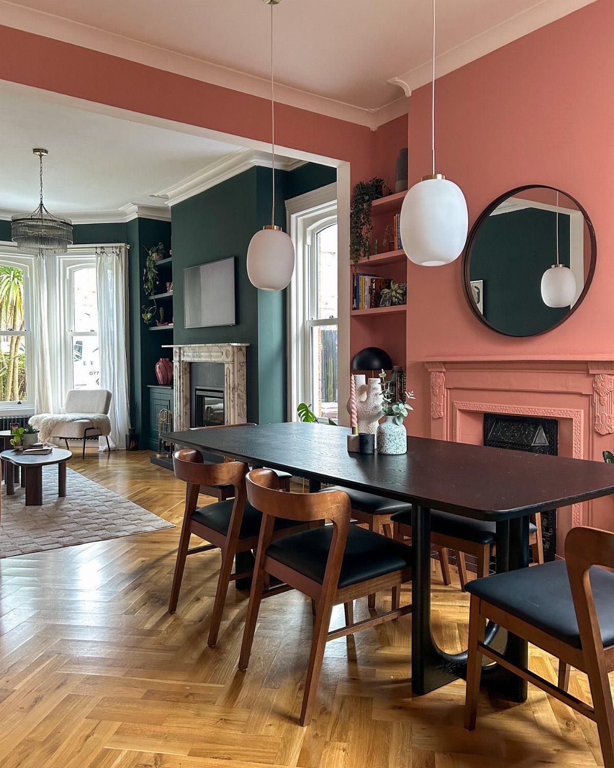 Dining room with contrasting coral and teal walls, dark table, and wooden chairs.