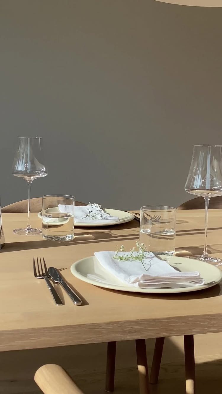 Elegant table setting with cream plates, wine glasses, and white floral accents.