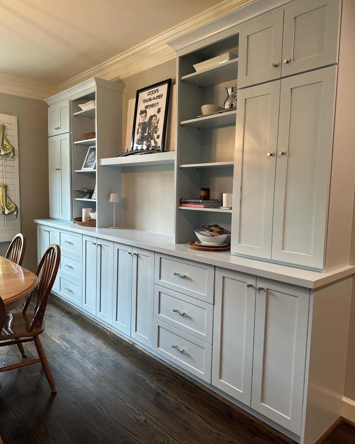 Light grey built-in dining room cabinetry with drawers, cupboards, and open shelving units.