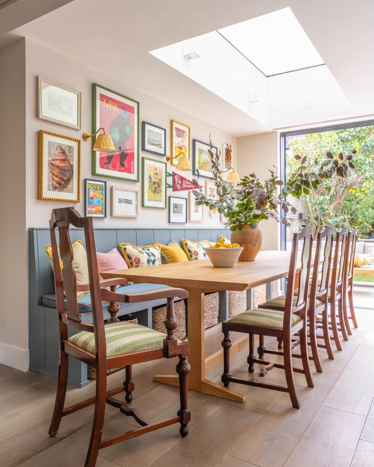 Blue built-in banquette with colorful pillows and a light wood dining table.