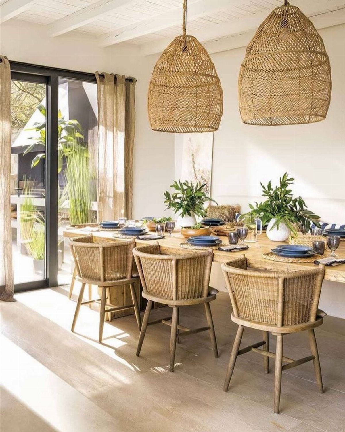 Dining room with woven chairs, wicker lamps, and green potted plants on table