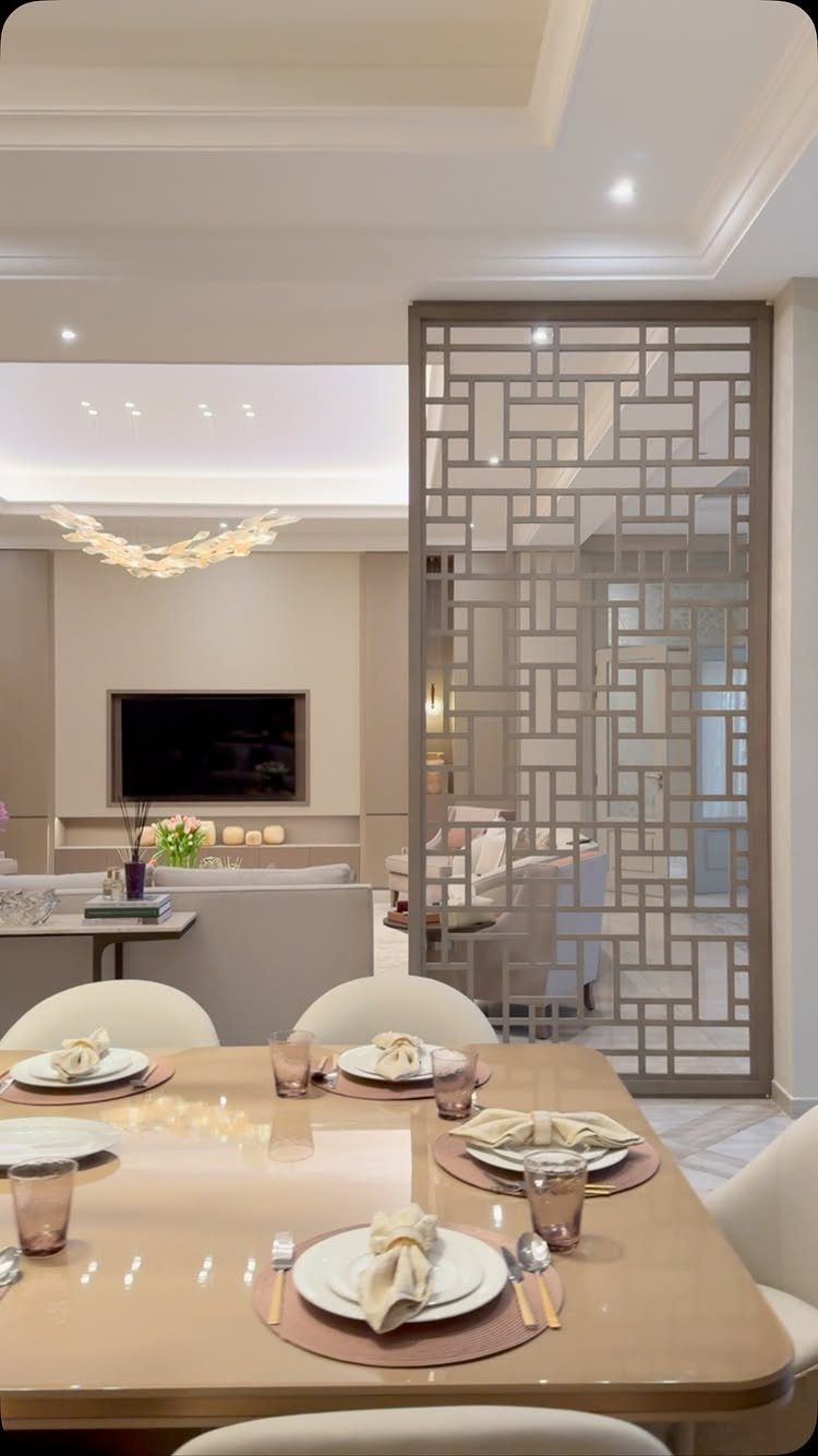 Dining table with place settings adjacent to a living room with a television.