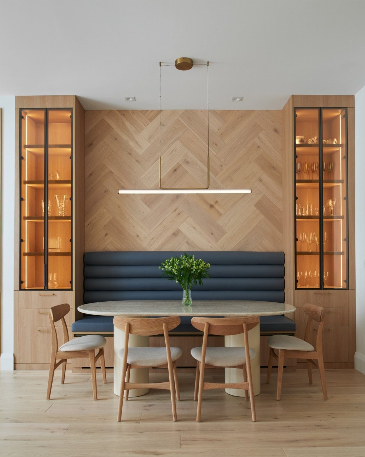 Navy blue banquette bench and wooden chairs around an oval dining table.