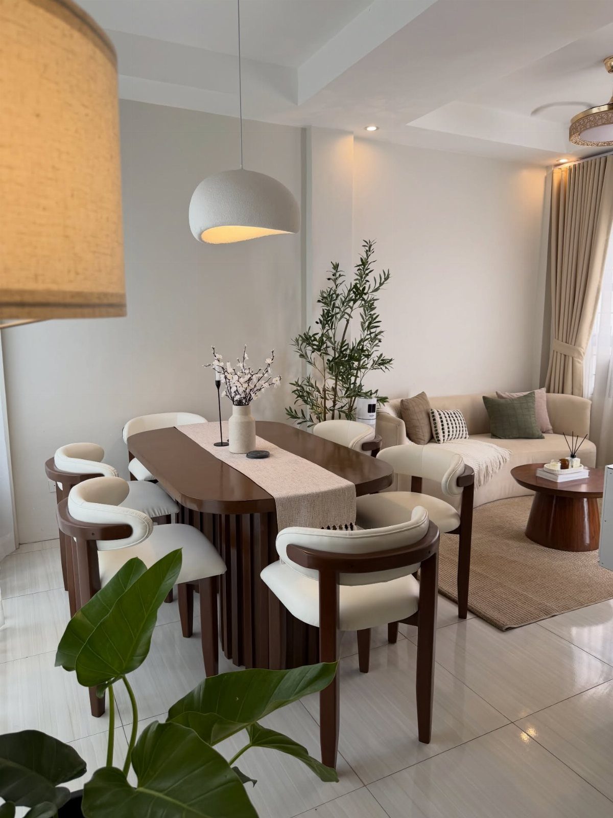Dark wood dining table and white upholstered chairs in a bright, modern room.