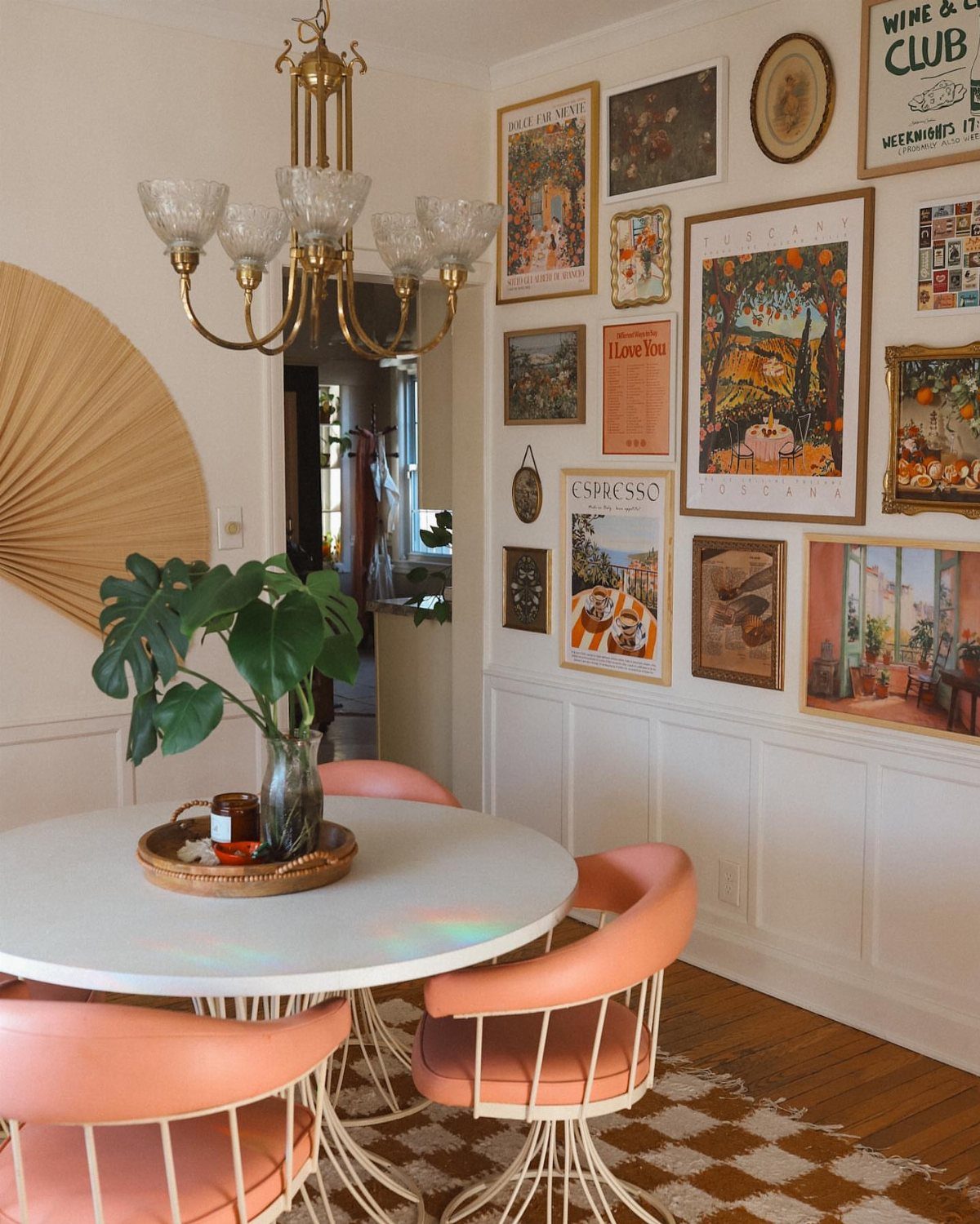 Dining room with peach chairs and a gallery wall of framed art prints.