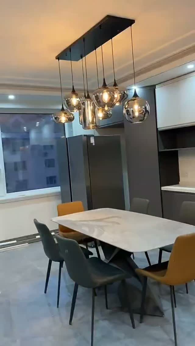 Modern dining room with a white table and unique silver globe pendant chandelier.