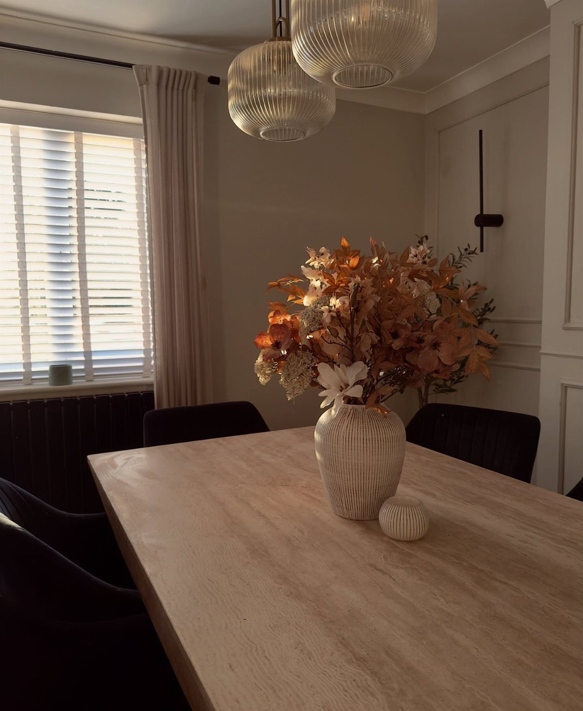 Dried autumn floral arrangement in a white vase on a wooden dining table