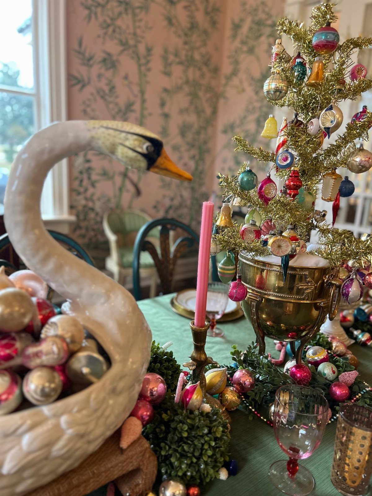 Festive dining table centerpiece with a swan filled with ornaments and a gold tree.
