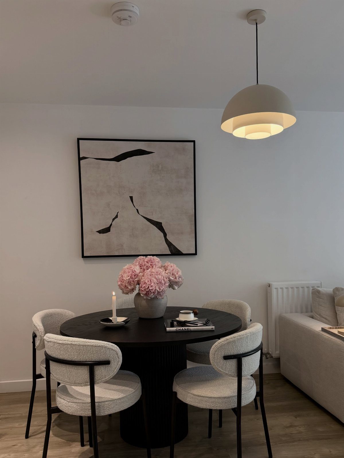 Round black dining table with low pink flower arrangement and candle centerpiece.