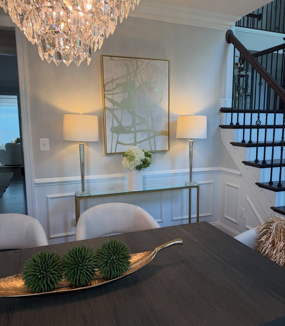 Gold boat-shaped bowl with green moss balls as a dining room table centerpiece.