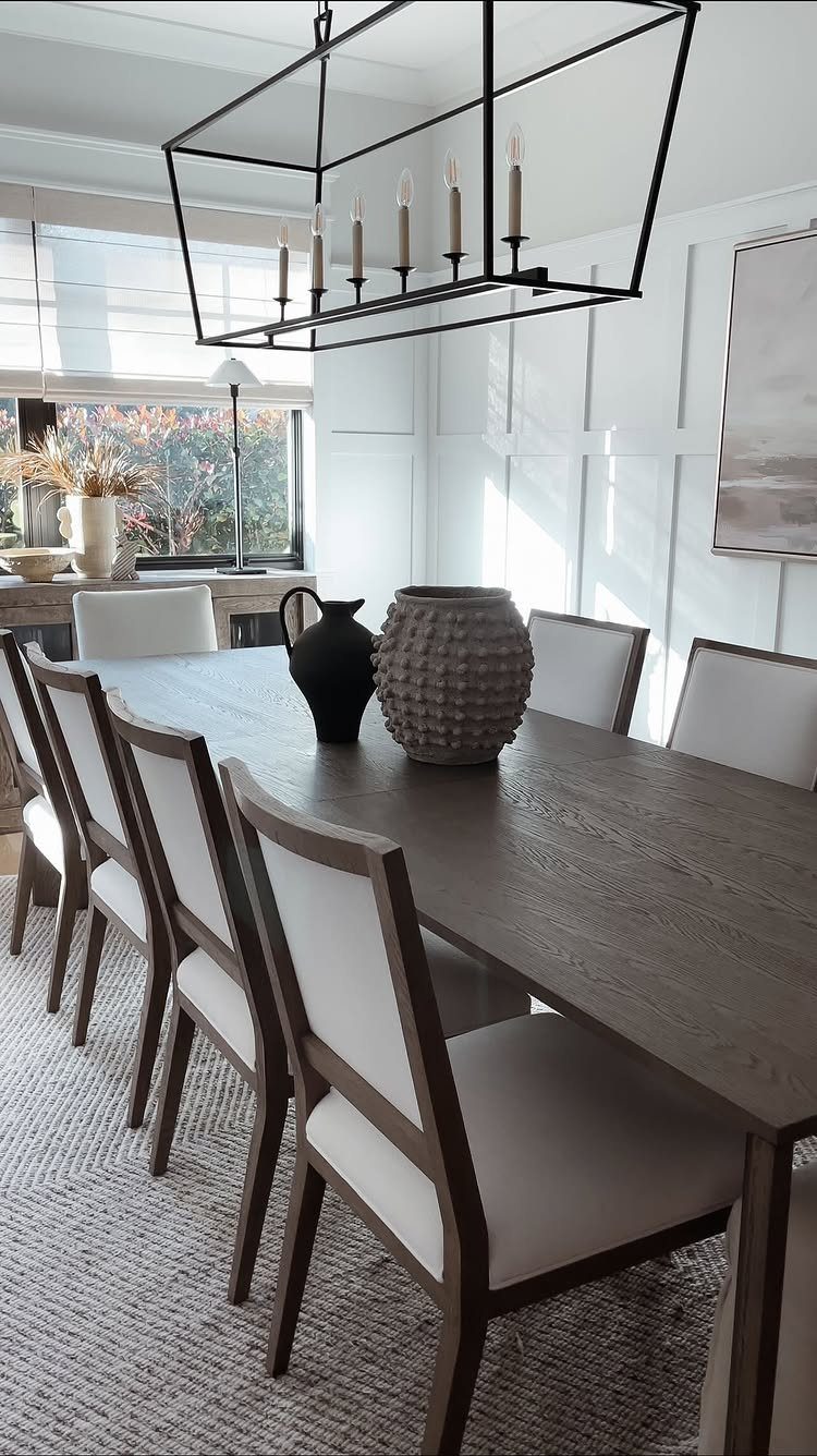 Two textured ceramic vases as a centerpiece on a wooden dining table.
