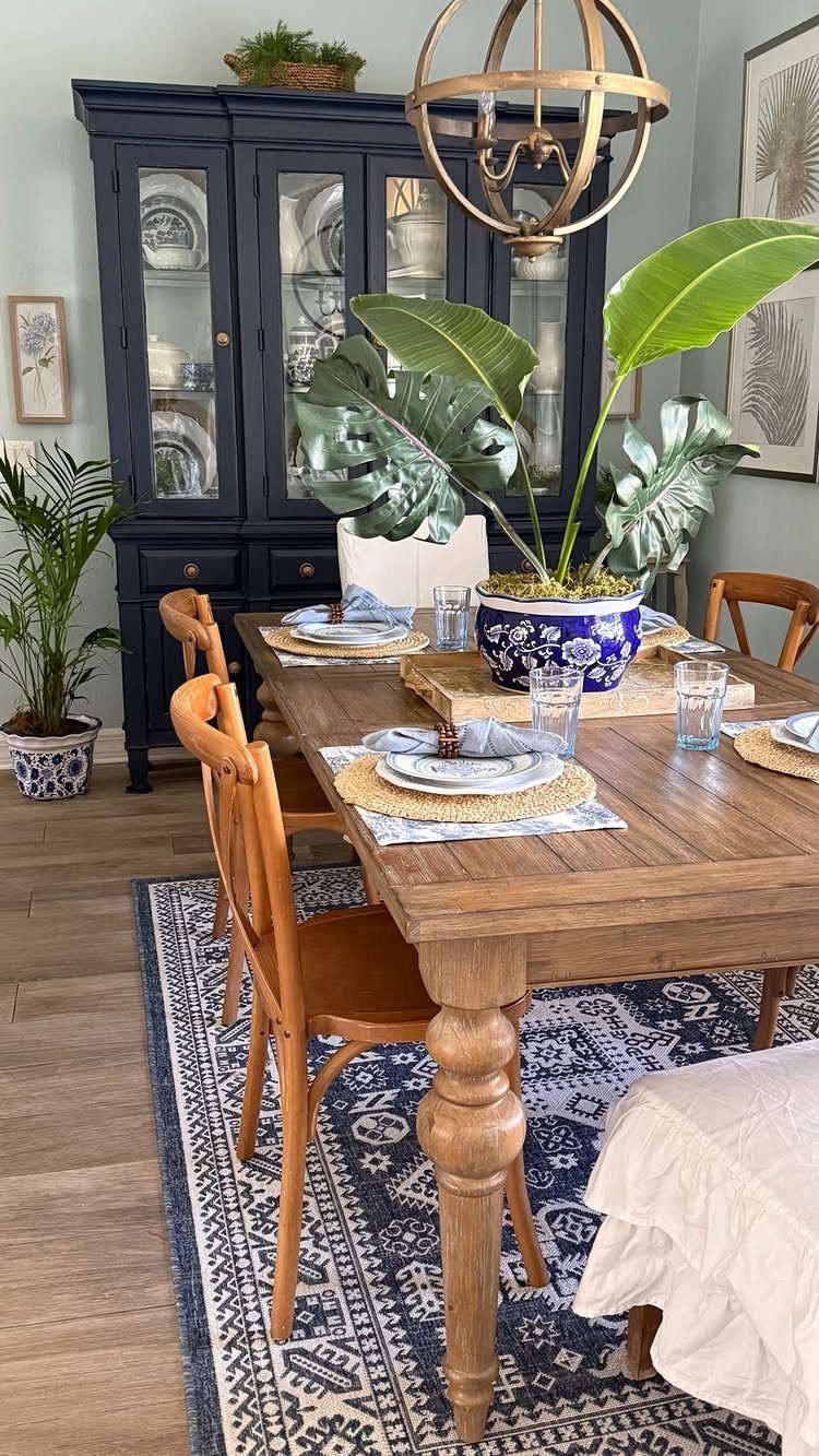 Large green potted plant in a blue ceramic pot on a wooden dining table.