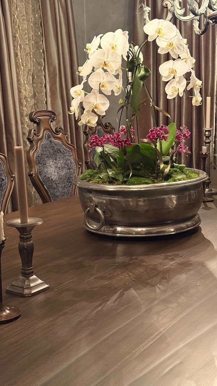 Silver metal basin centerpiece with white and pink orchids on a wooden table