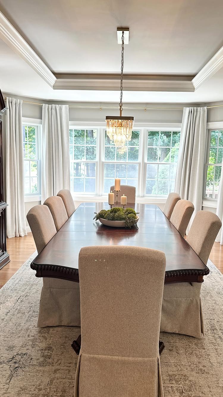 Dark wood dining table with a greenery bowl and white pillar candle centerpiece.