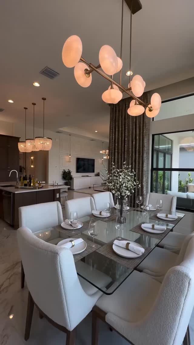 Modern gold chandelier with glowing orbs hanging over a glass dining table
