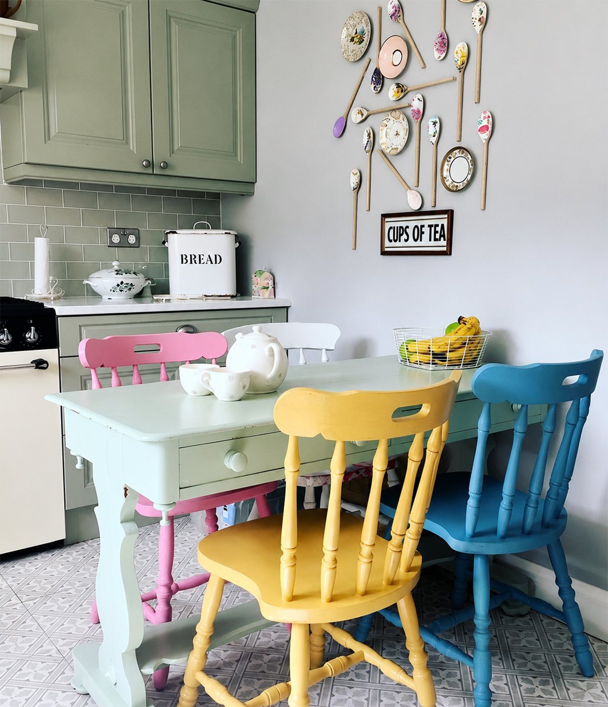 Colorful pink, yellow, and blue wooden chairs around a mint green dining table.
