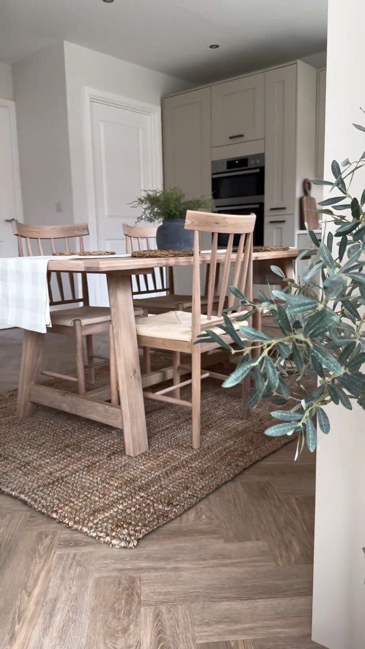 Wooden dining table and chairs placed on a brown woven jute area rug
