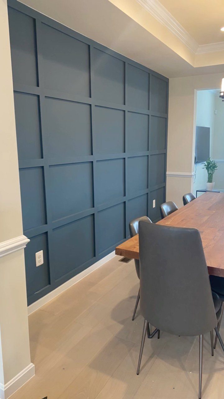 Navy blue grid-paneled accent wall in a dining room with wooden table.