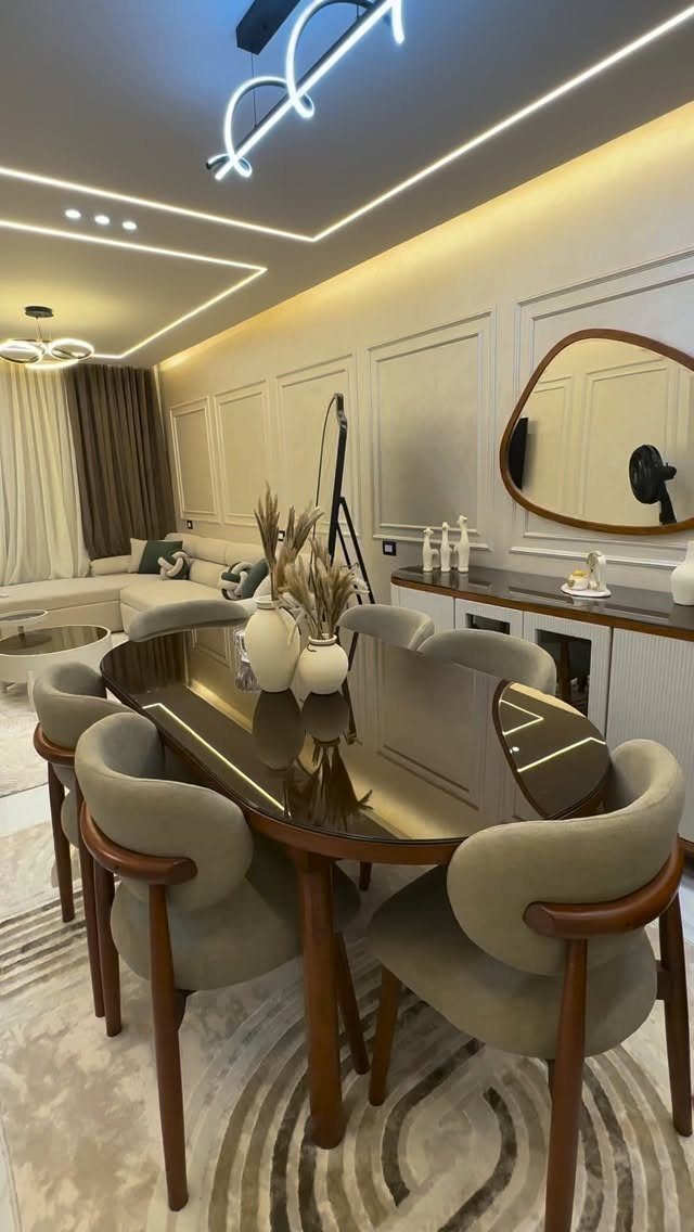 Modern dining room with off-white paneled walls, dark oval table, and grey chairs.