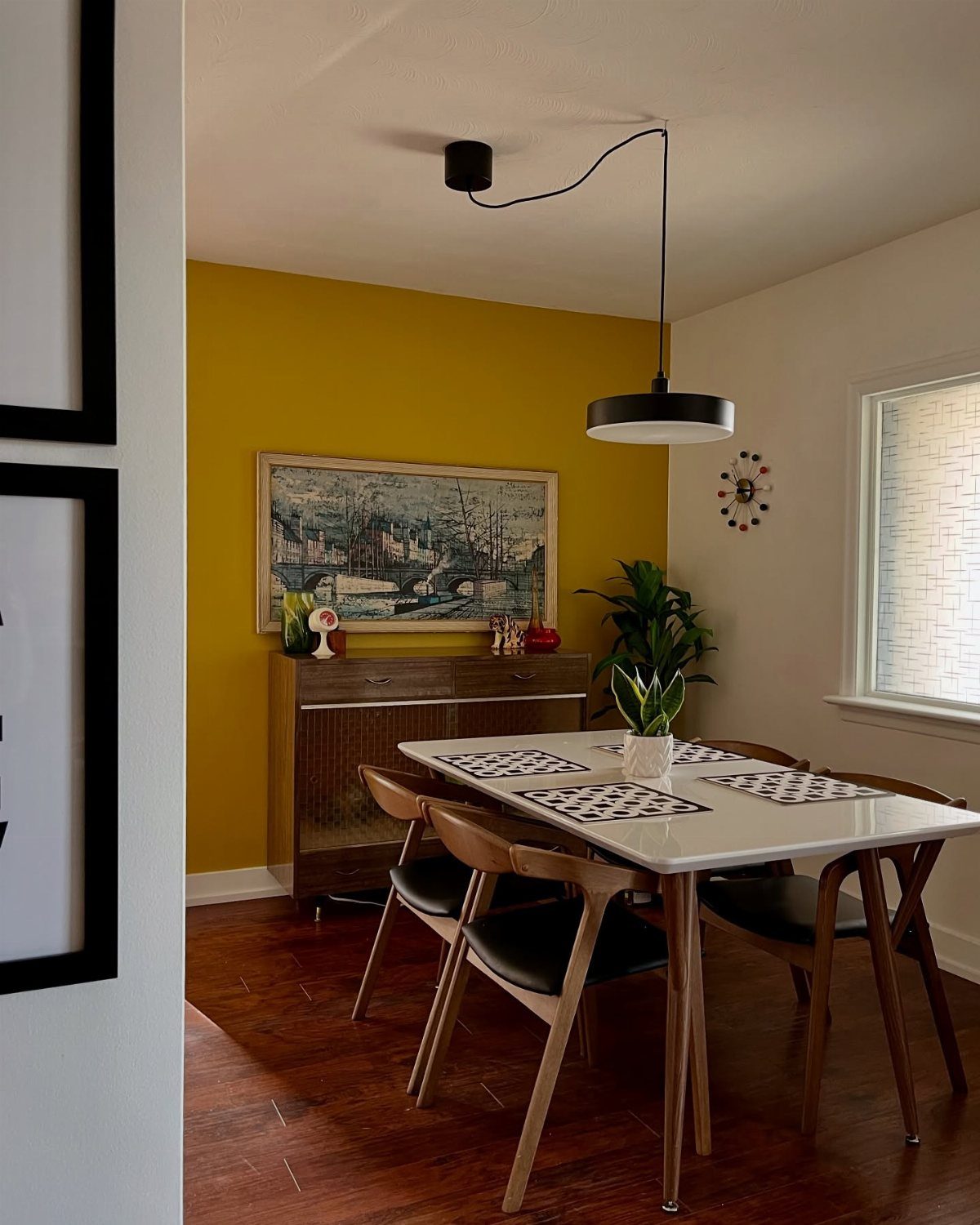 Deep yellow accent wall in a dining room with mid-century modern furniture.