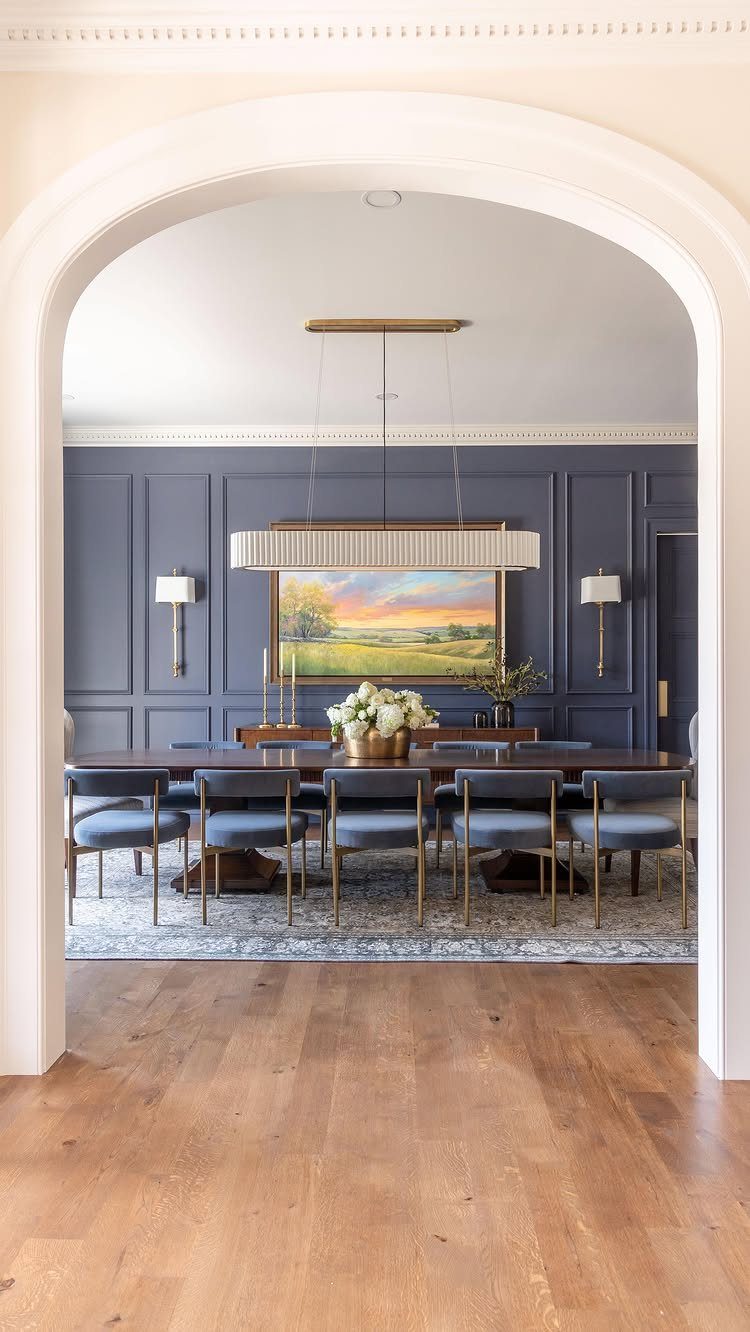 Navy blue paneled dining room walls with a dark wood table and blue chairs.