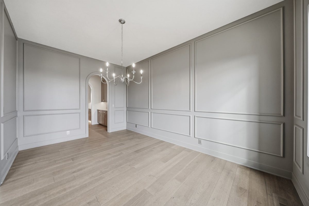 Light gray dining room walls with decorative molding and light hardwood floors.