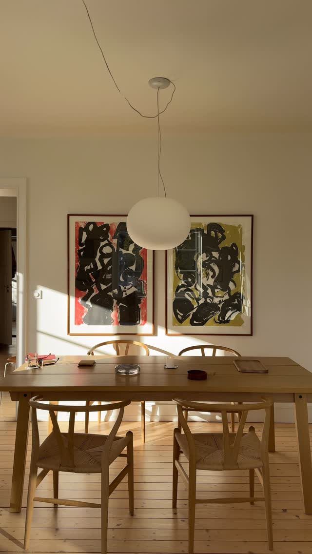 White dining room walls with a wooden table and abstract art paintings.