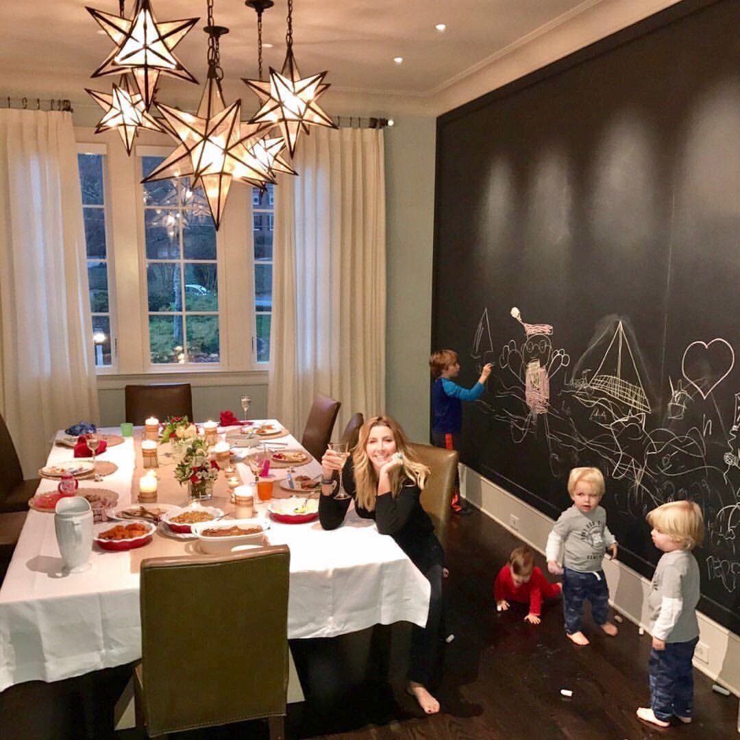 Large black chalkboard wall with drawings in a dining room with children.