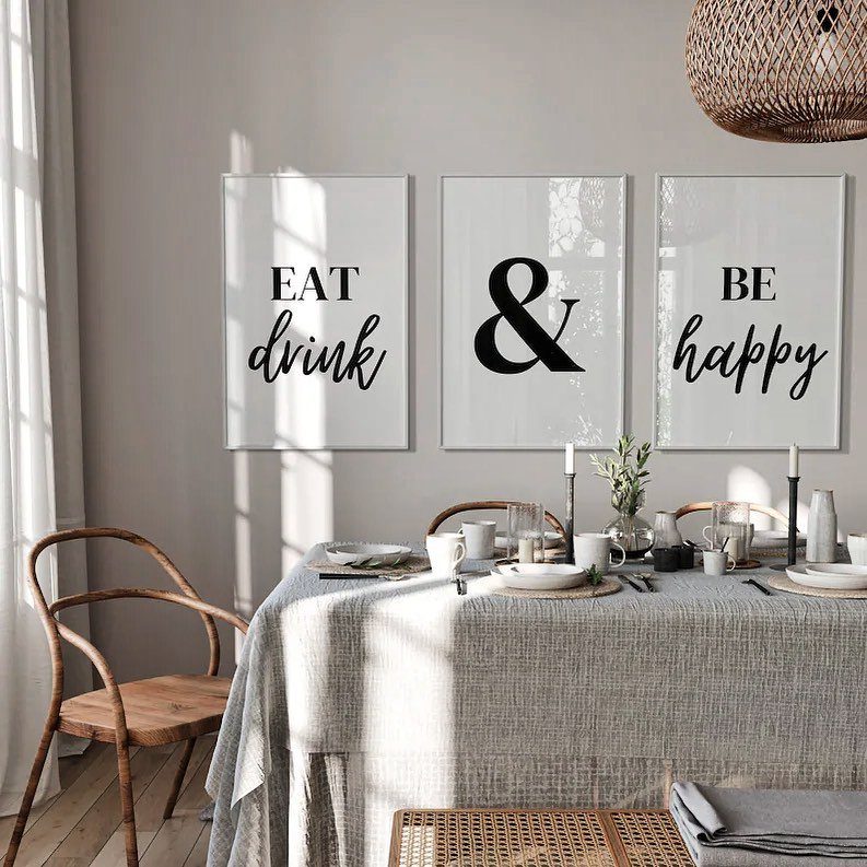 Three framed typographic posters on a grey wall above a set dining table.