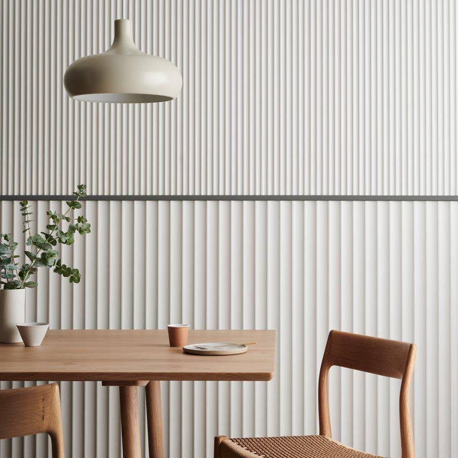 White vertical ribbed textured wall panels in a dining room with wooden furniture.